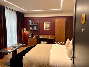 A hotel room with a bed, desk, chair, and a small table with a lamp. - Faubourg 21 – The Leading Hotels of the World (Brussels)