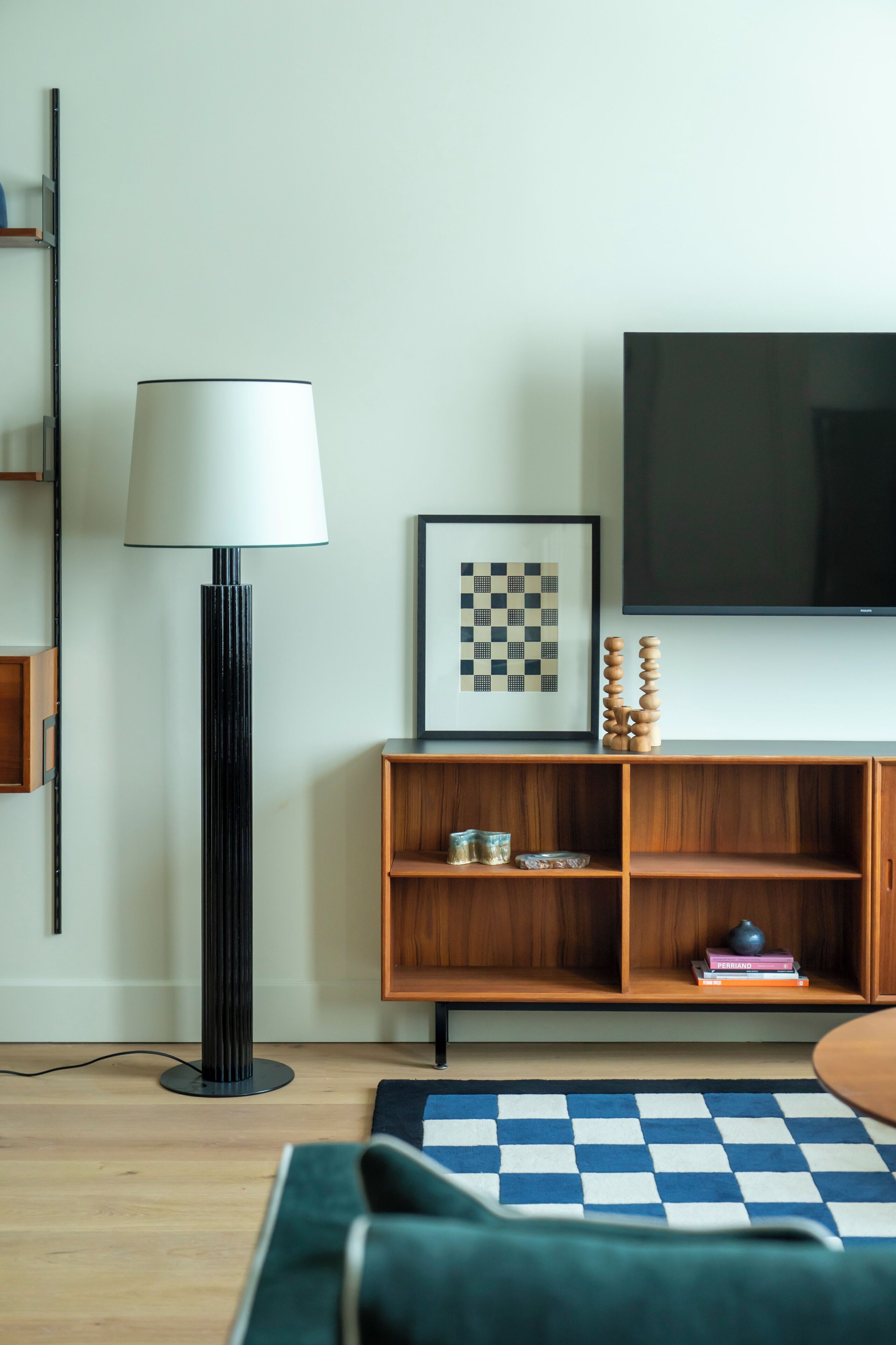 A modern living room with a television, a lamp, a framed artwork, and a wooden cabinet.
