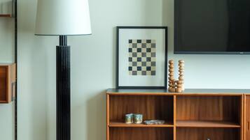 A modern living room with a television, a lamp, a framed artwork, and a wooden cabinet.