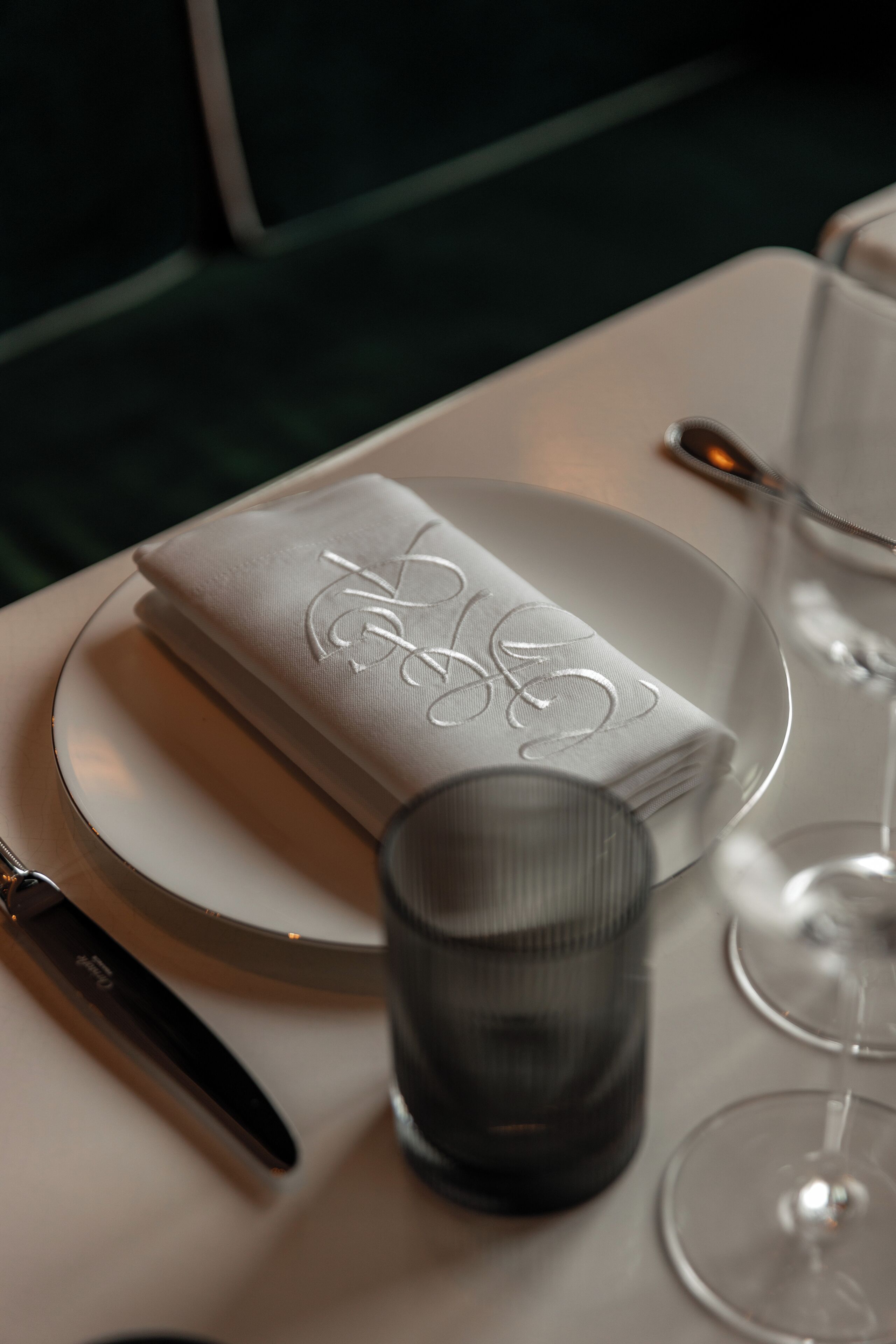 A table with a folded napkin, a glass, and a spoon.
