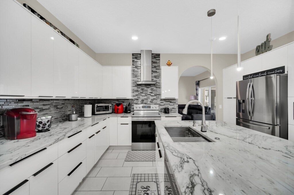 A modern kitchen with white cabinets, a stainless steel range, and a marble countertop.