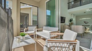 A modern apartment with a balcony, white furniture, and a kitchen area.