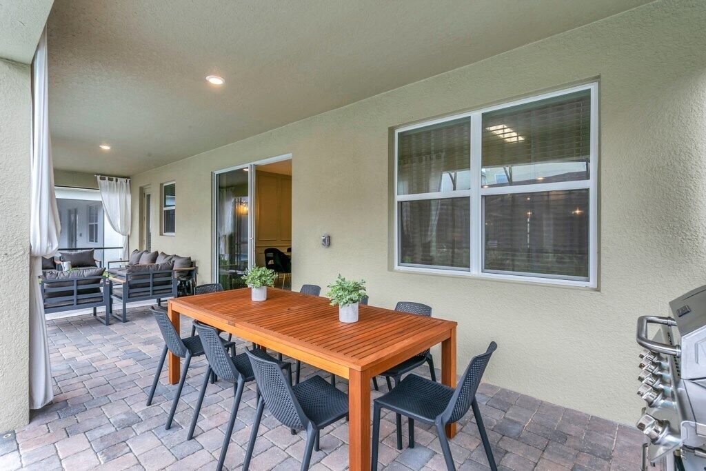 Un patio al aire libre con una mesa y sillas de madera, una parrilla y vistas del interior.