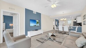 Ein modernes Wohnzimmer mit Fernseher, Sofa und Essbereich.