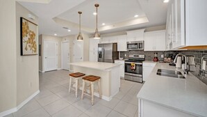 A modern kitchen with white cabinets, stainless steel appliances, and a central island with stools.