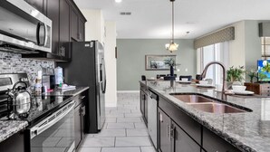 A modern kitchen with dark cabinetry, stainless steel appliances, and a granite countertop.