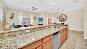 A spacious kitchen with granite countertops, wooden cabinets, and a stainless steel dishwasher. - Paradise Palms Resort  Town home With Pool Only 8 Minutes To Disney (Kissimmee)