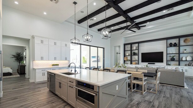 Una cocina moderna con una isla central, muebles blancos y un rincón comedor con sofá y sillas.