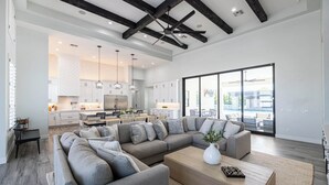 Una sala moderna con un sofá modular, una mesa de centro y vistas a la cocina y al área exterior.