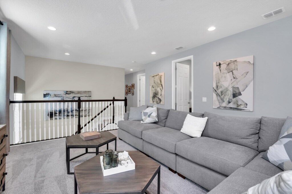 A modern living room with a grey sectional sofa, a coffee table with a tray, and abstract art on the walls.