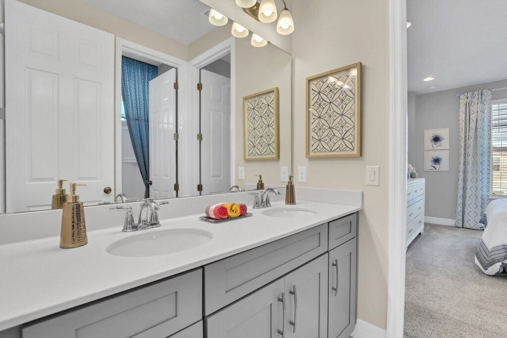A bathroom with a double sink vanity, a large mirror, and decorative wall art.
