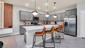 A modern kitchen with a central island, stainless steel appliances, and pendant lighting.