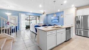 A modern kitchen with a central island, stainless steel appliances, and pendant lighting. - Ultimate 5 Bedroom Windsor Island Resort Pool  home (Davenport)