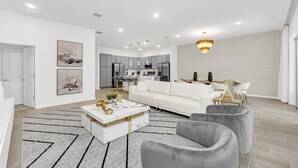 Een moderne woonkamer met een witte bank, grijze fauteuils en een marmeren salontafel.