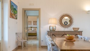 A dining area with a wooden table, white chairs, a decorative mirror, and a lamp.
