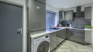 A modern kitchen with a built-in washing machine, a sink, and a microwave.