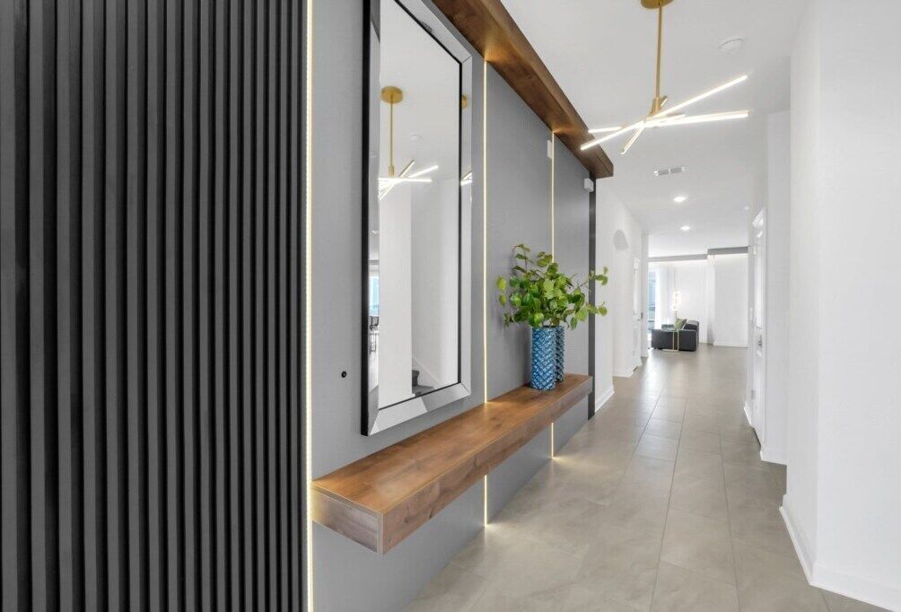 A modern hallway with a wooden bench, a mirror, and a potted plant.