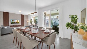 Un comedor moderno con una mesa de madera dispuesta para cuatro personas, rodeada de sillas blancas.