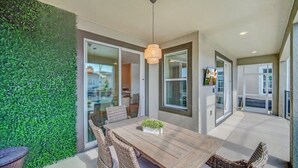 Un comedor con mesa de madera, sillas de mimbre, lámpara colgante y pared verde.