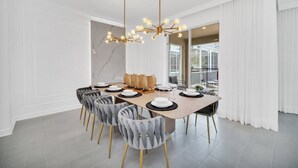 Une salle à manger moderne avec un mur en marbre, un lustre et une grande fenêtre agrémentée de rideaux.