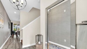 Un pasillo moderno con una escalera, piso de madera y una alfombra azul estampada.