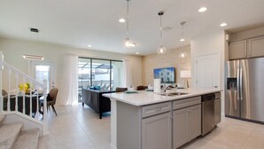A modern kitchen with a central island, stainless steel appliances, and pendant lighting.