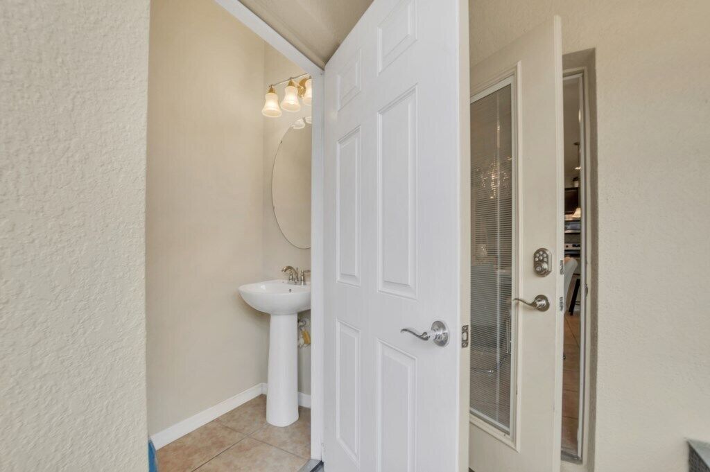 Un baño con un lavamanos blanco, un espejo y una puerta que da a un armario.