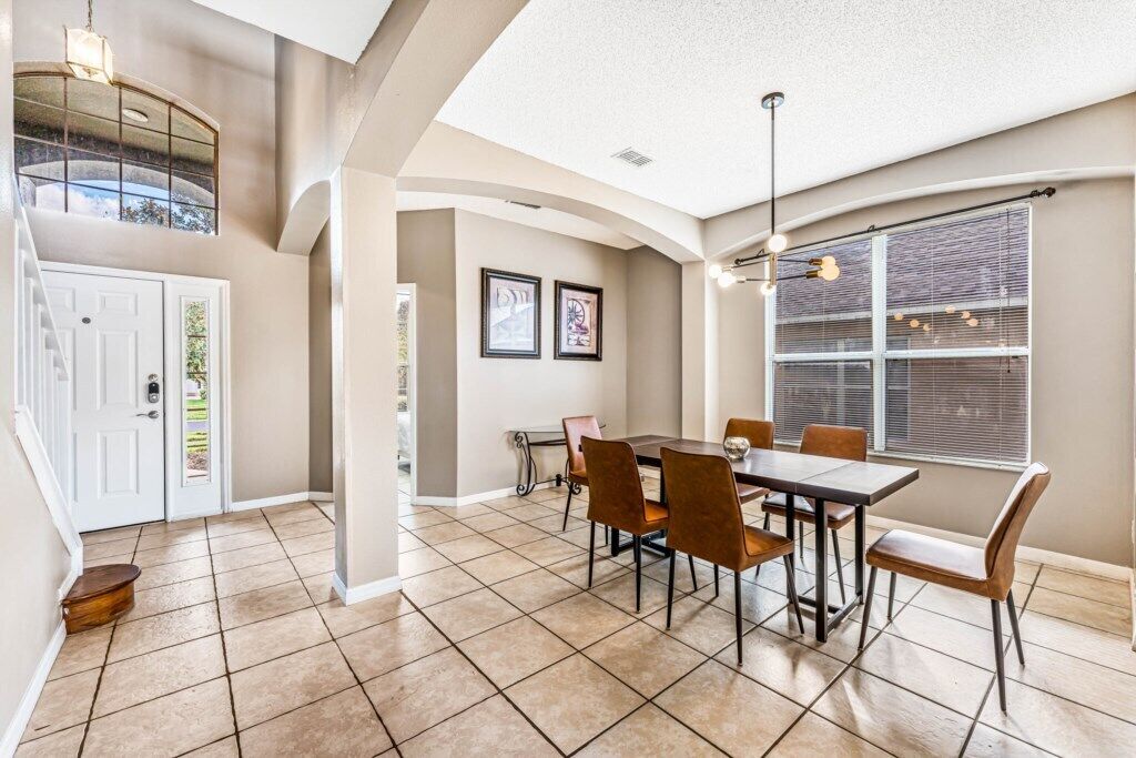 A dining area with a table and chairs, a window with blinds, and a door with a mailbox.