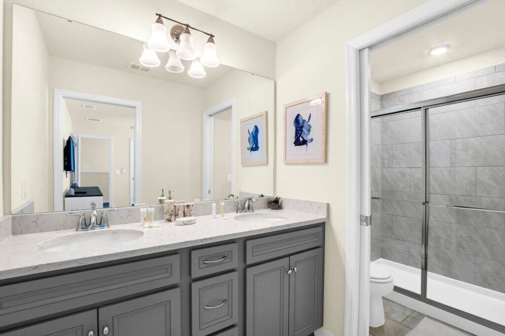 A bathroom with a large mirror, two sinks, and a shower area.