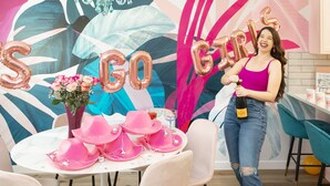 Un evento de celebración con globos que deletrean “SING GIRL” y una mujer sosteniendo una botella.