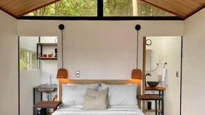 A modern bedroom with a large bed, bedside tables, a mirror, and a window. - La Comarca Guatape (El Peñol)