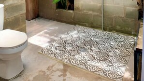 A small, enclosed bathroom with a concrete shower, a toilet, a sink, and a patterned floor. - La Comarca Guatape (El Peñol)