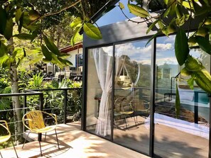 A modern outdoor seating area with glass walls, a view of a mountainous landscape, and lush greenery. - La Comarca Guatape (El Peñol)
