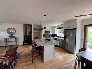 A modern kitchen with a central island, stainless steel appliances, and a view to the outdoors. - Charming 3-bedroom Mid-Century (Rapid City)