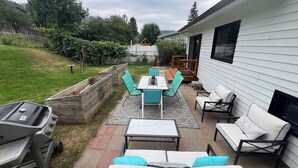 En udendørs terrasse med grill, et bord med stole og en sofa.