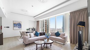 A modern living room with a sofa, two round coffee tables, a flat-screen TV, and a large window with a city view. - ME DO RE residence (Dubai)