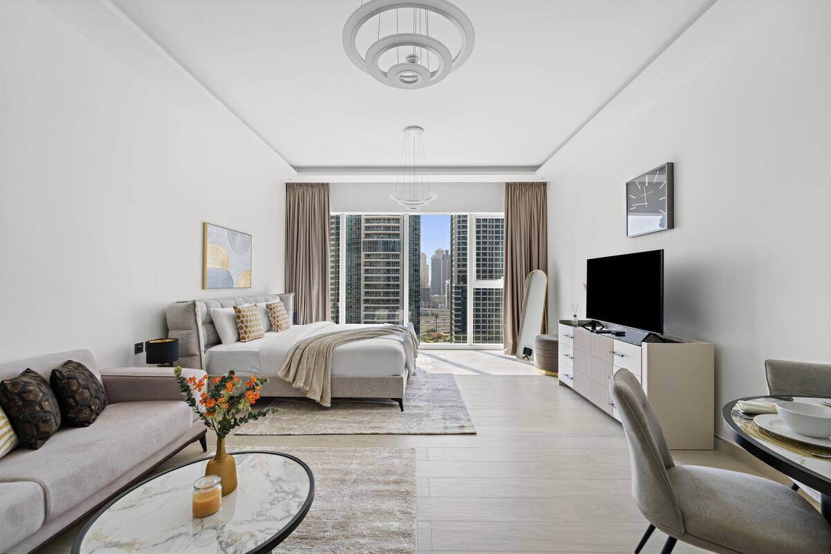 A modern living room with a sofa, a coffee table, a TV, and a dining area.