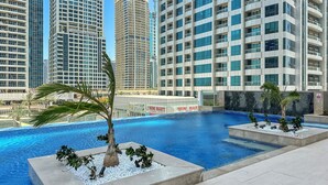 A rooftop pool with palm trees, surrounded by high-rise buildings. - ME DO RE residence (Dubai)