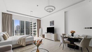 A modern hotel room with a large bed, a dining area, and a TV. - ME DO RE residence (Dubai)