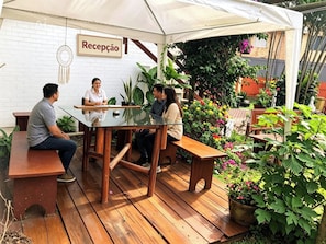 A reception area with a white brick wall, a sign reading 'Recepção,' and a dreamcatcher decoration. - Pousada Aurema (Imbituba)
