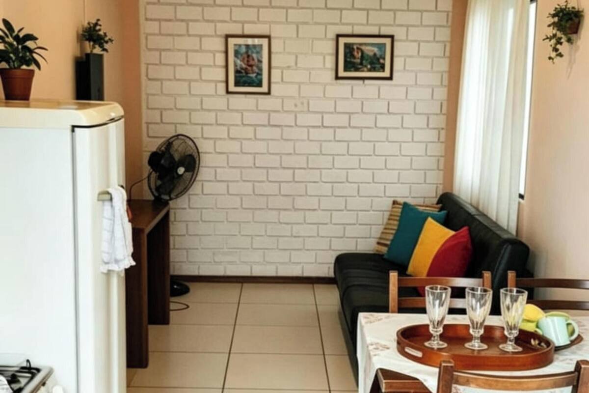 A compact kitchen with a stove, a fan, and a dining area with a table set for three.