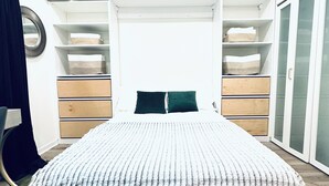 Ein Schlafzimmer mit Bett, Deckenventilator, Einbauschränken und einem Kleiderschrank.