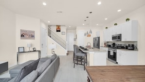 A modern kitchen with white cabinets, a central island, and a stainless steel refrigerator. - Amazing and unique Dream House Experience just 5 Min to Disney Parks  (Kissimmee)