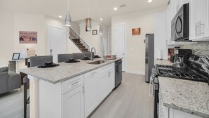 A modern kitchen with white cabinets, granite countertops, stainless steel appliances, and pendant lighting. - Amazing and unique Dream House Experience just 5 Min to Disney Parks  (Kissimmee)
