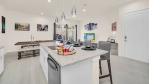 A modern kitchen with a central island, pendant lighting, and artwork on the walls. - Amazing and unique Dream House Experience just 5 Min to Disney Parks  (Kissimmee)