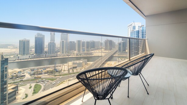 A balcony with two black wireframe chairs, a city view, and a modern building in the background. - Elite Downtown Residences (Dubai)