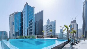 A rooftop pool with a city skyline in the background. - Elite Downtown Residences (Dubai)