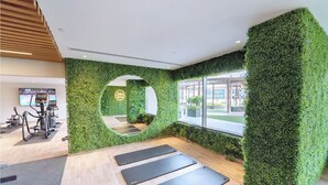 A gym with green walls, exercise equipment, and a large mirror. - Elite Downtown Residences (Dubai)