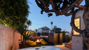 A hot tub in a backyard with a wooden fence, a tree, and a house in the background. - Ocean Beach Spanish Gem | Walk to beach pier shops (San Diego)