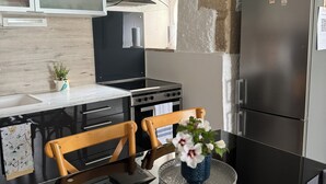 Eine moderne Küche mit schwarzem Arbeitsplatz, Holzstühlen, einem Glastisch und einem Kühlschrank.